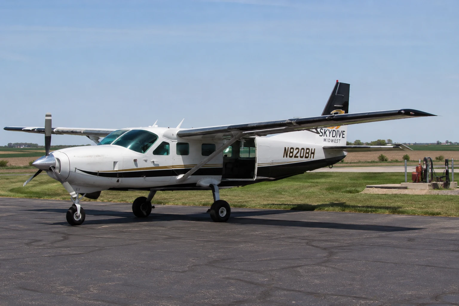 Single-engine turboprop skydiving aircraft parked on a rural airfield under clear daylight